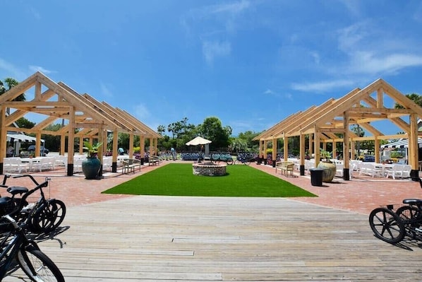 A wooden deck with a central lawn and two wooden pergolas on either side. - Cozy 30A Studio for Two, by Rosemary Bch. Walk to Beach/Dining/Heated pool/shops (Seacrest)