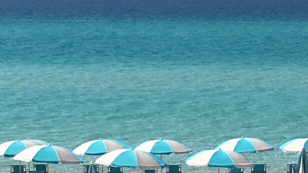 A beach with multiple umbrellas and lounge chairs.