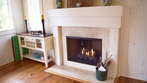 Una chimenea con repisa, un mueble verde para guardar cosas y un jarrón con plantas secas.
