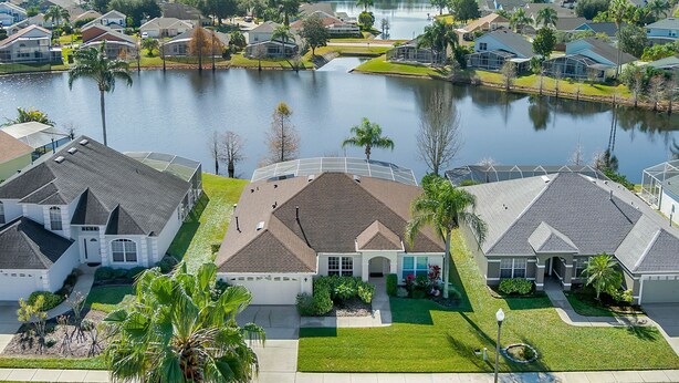 Un quartier résidentiel avec des maisons situées près d’un lac, caractérisé par de belles pelouses bien entretenues et des palmiers.