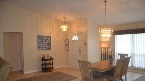 Un coin repas avec une table et des chaises en bois, un lustre et un tableau au mur.