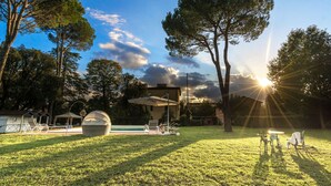 Un jardin avec une piscine, des chaises longues et des parasols.