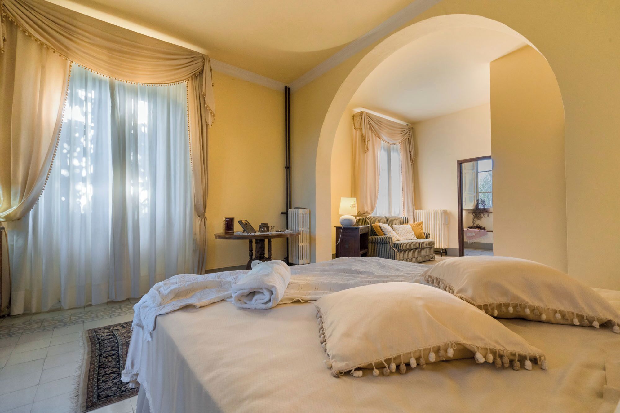 Une chambre d’hôtel avec deux lits, une petite table, une chaise et une fenêtre avec des rideaux.