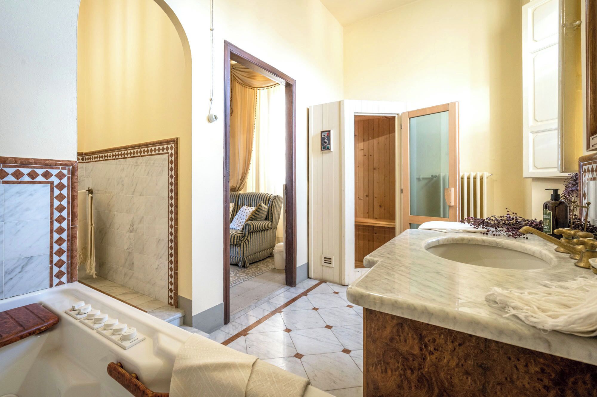 A bathroom with a bathtub, a shower, a wooden door, and a wooden bench.