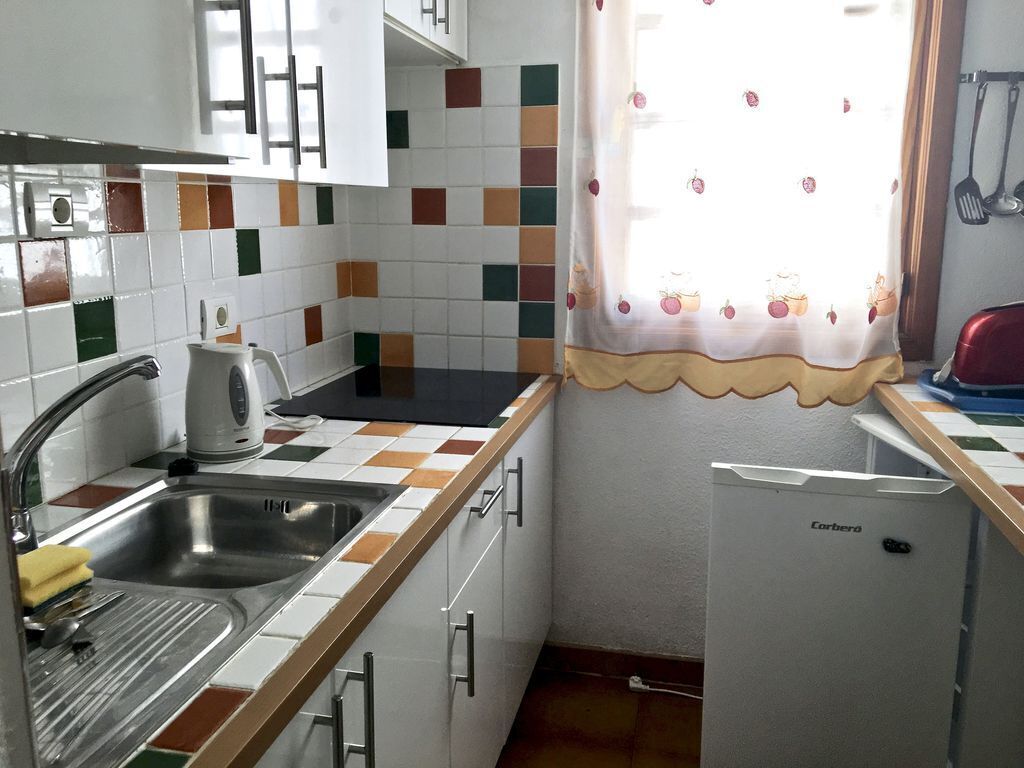 A kitchen with a sink, a toaster, and a refrigerator.