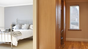 Une chambre à coucher avec un lit en métal, une armoire en bois et une fenêtre équipée de stores.