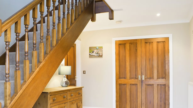 Un escalier en bois, avec une lampe et un meuble en bois.