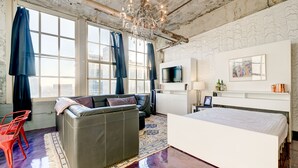Una habitación de hotel moderna con una cama grande, un sofá, un televisor y una araña.