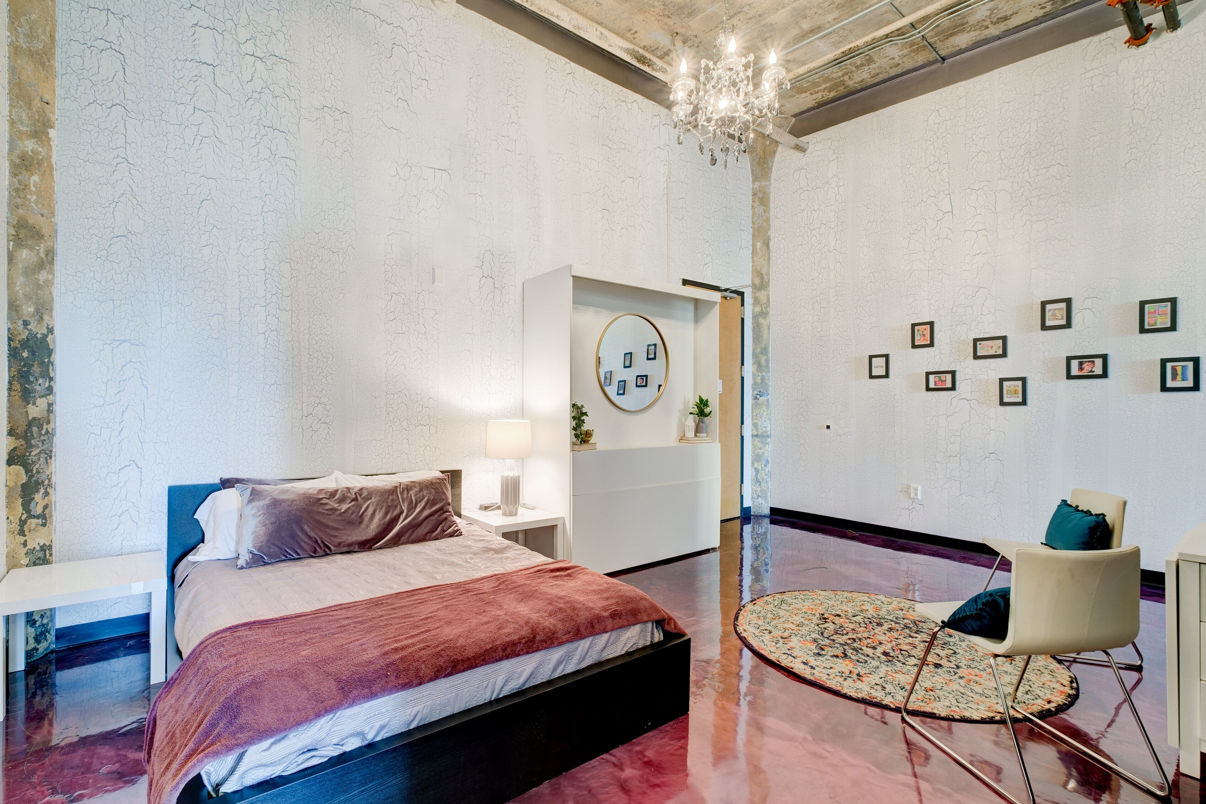 A modern bedroom with a bed, bedside table, and a round mirror.