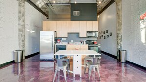 Una cocina moderna con una isla central, electrodomésticos de acero inoxidable y suelo de mármol.