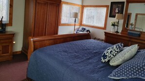 A bedroom with a large bed, wooden wardrobe, and a window with blinds. - Claytor Lake Hideaway (Pulaski)