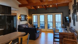 A spacious living area with a dark sofa, wooden dining table, and a ceiling fan. - Claytor Lake Hideaway (Pulaski)