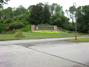 A sign for 'Peninsula' with a stone base and a grassy area in front.