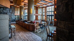 Een ruime lobby met een centraal gelegen bar, stenen zuilen en grote ramen die natuurlijk licht binnenlaten.