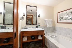 A bathroom with a wooden vanity, a large mirror, a bathtub, and a framed picture on the wall. - 2 BR Lodge at Spruce Peak (Stowe)