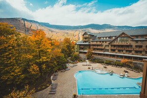 A resort with a swimming pool, lounge chairs, and a mountainous backdrop. - 2 BR Lodge at Spruce Peak (Stowe)