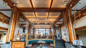 Een ruime lobby met een gebogen groene bank, een stenen openhaard en een houten trap.
