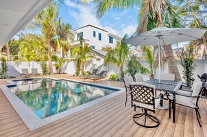 Una piscina al aire libre, sombrillas, sillones reclinables de piscina