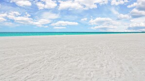 A wide sandy beach with a clear blue sky and scattered clouds. - Captain's Quarters at Anna Maria Island Inn (Bradenton Beach)