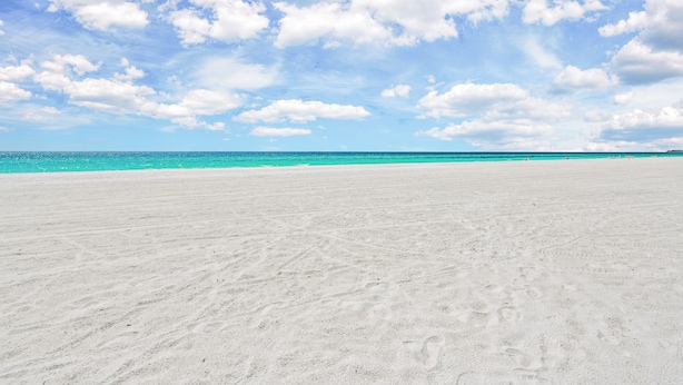 A wide sandy beach with a clear blue sky and scattered clouds. - Captain's Quarters at Anna Maria Island Inn (Bradenton Beach)