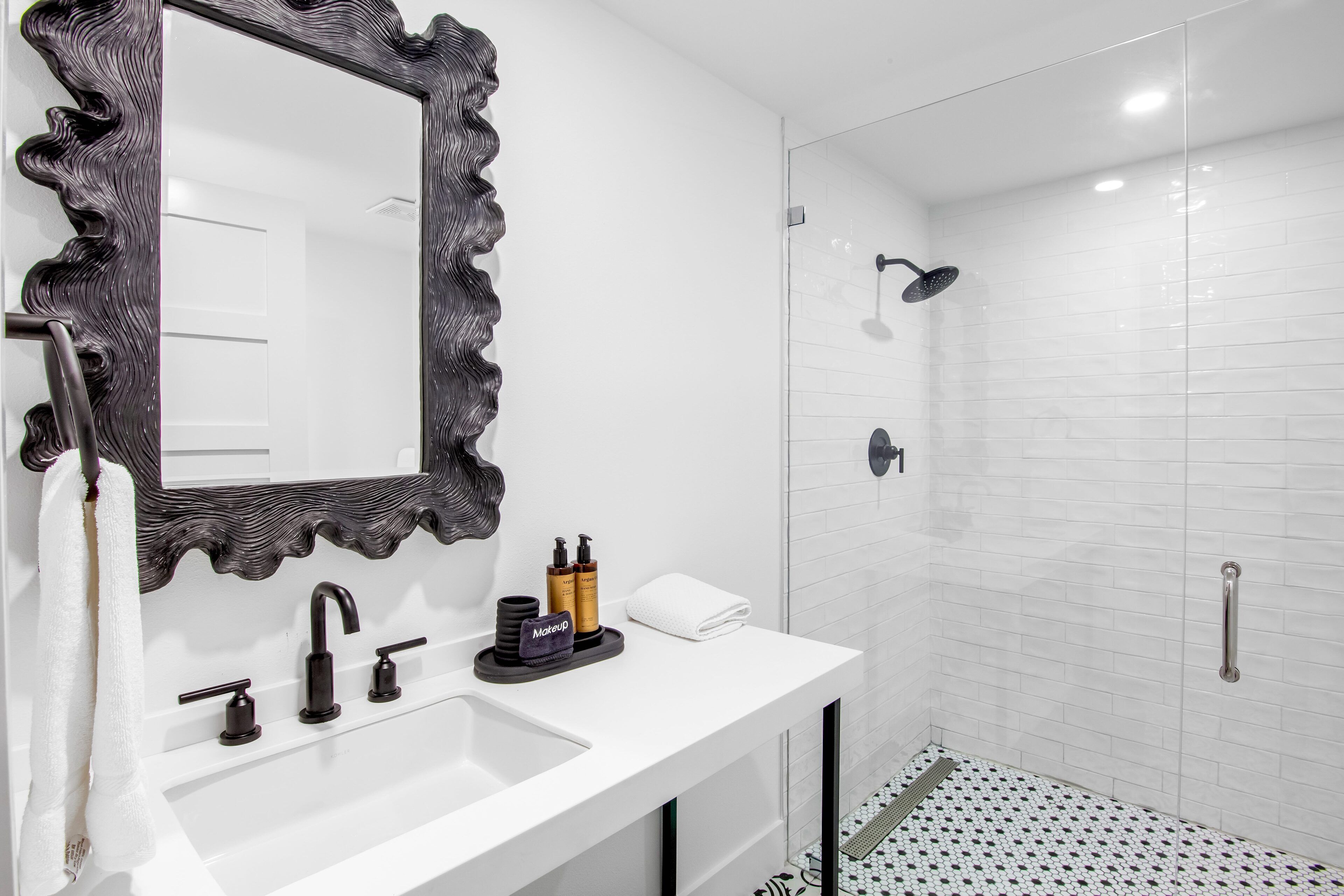 A modern bathroom with a large mirror, a sink, and a shower.
