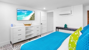 A bedroom with a bed, a dresser, a TV, and a window. - Captain's Quarters at Anna Maria Island Inn (Bradenton Beach)