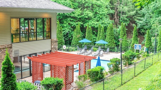 A residential property with a swimming pool, outdoor seating, and a covered patio area.