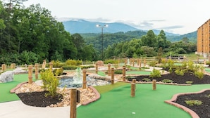 A miniature golf course with multiple holes, wooden obstacles, and a water feature.