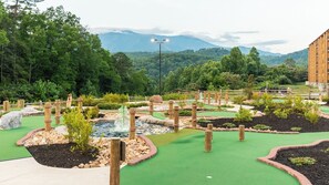 A miniature golf course with multiple holes, wooden obstacles, and a water feature. - MountainLoft™ - 1 Bedroom Deluxe Villa (Gatlinburg)