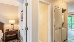 A hotel room with a bed, bedside table with a lamp, a wardrobe, and a view of the outdoors.