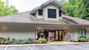 A building with a gabled roof, a front entrance with glass doors, and an American flag.