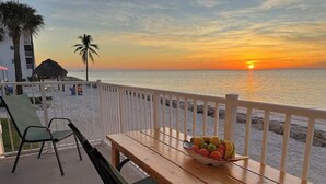 Ein Holztisch mit Obstschale auf einem Balkon mit Blick auf das Meer bei Sonnenuntergang.