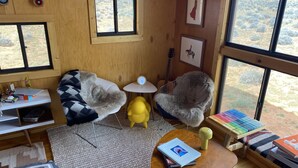 Une pièce confortable avec une grande fenêtre, un bureau en bois, une chaise, une petite table et une bibliothèque.