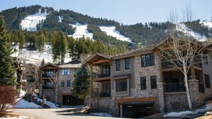 A multi-story lodge with stone and wood construction, a covered outdoor area, and a view of a snow-covered mountain. - Outpost: Grand View 3140 - Air conditioning! (Jackson)