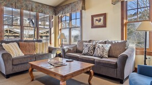 A cozy living room with two sofas, a coffee table, and large windows offering a view of a mountain cabin. - Outpost: Grand View 3140 - Air conditioning! (Jackson)
