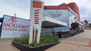 Das Außengelände des Mogano Express Hotels mit auffälliger Beschilderung, moderner Architektur und einer gepflegten Eingangsbereich.