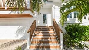 A staircase leading to a white building with a wooden railing and a door. - Beach Time AMI by AMI Locals (Holmes Beach)
