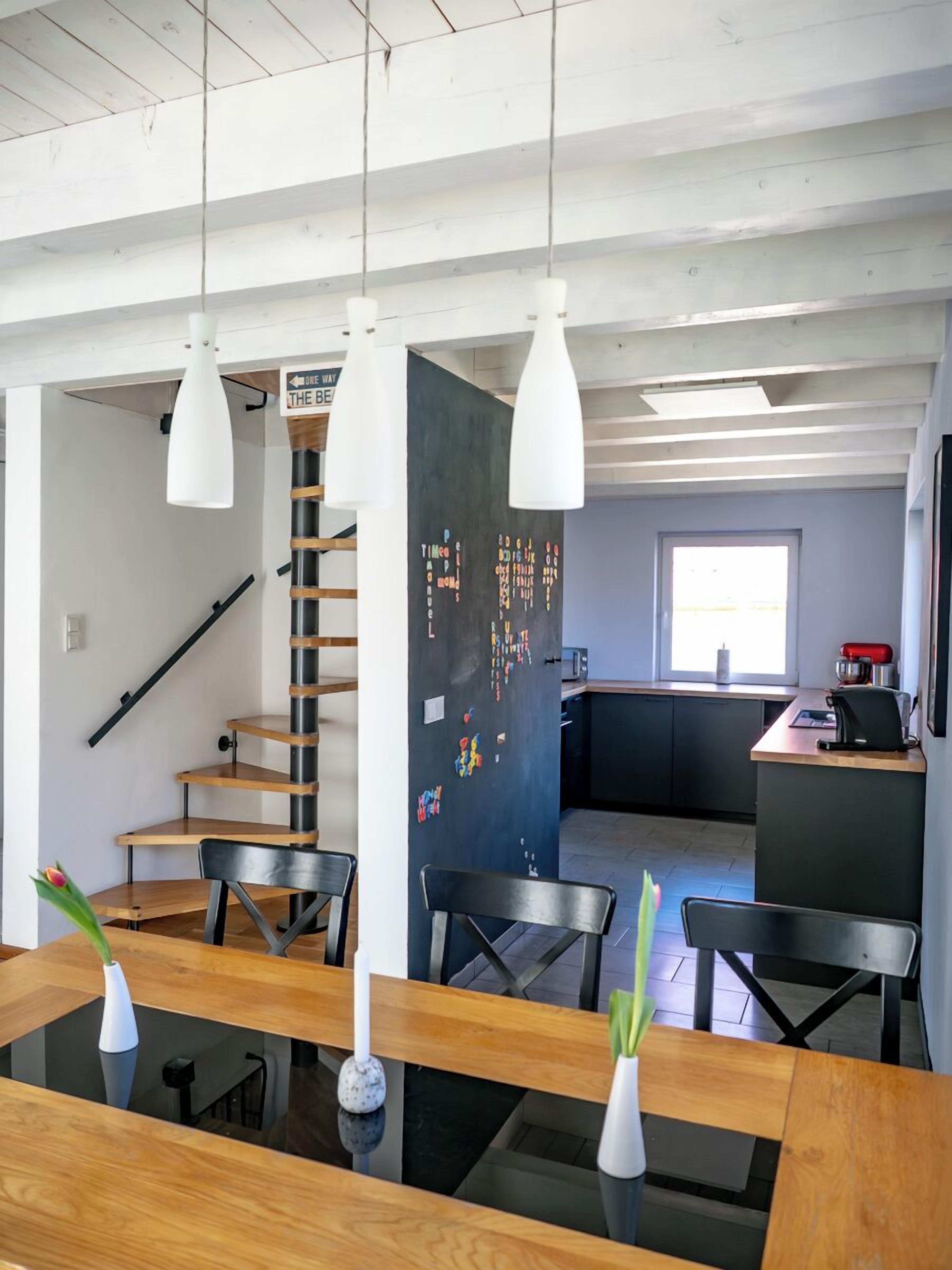 Een moderne keuken met een prikbord, houten meubels en hanglampen.