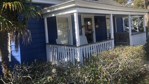 Une maison avec un porche couvert, une petite terrasse et une boîte aux lettres.