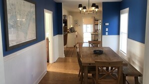 Un coin repas avec une table et des chaises en bois, un lustre et une carte accrochée au mur.