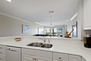 Een moderne keuken met een dubbele spoelbak, witte kastjes en een vaatwasser.
