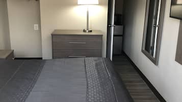 A hotel room with a large bed, a bedside table with a lamp, a wardrobe, and a mirror on the wall.