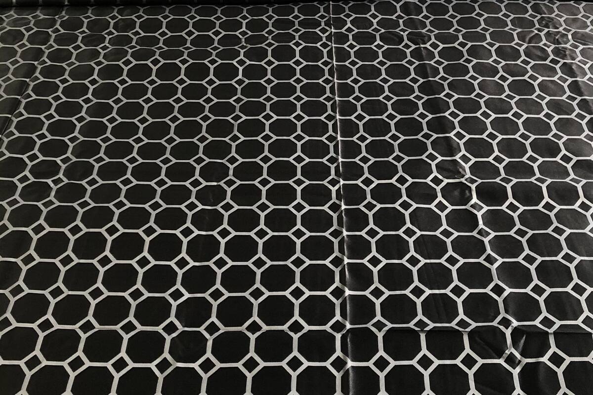 A bed with white pillows and a black and white patterned bedspread.