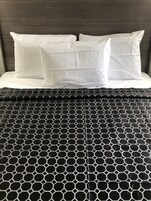 Una cama con almohadas blancas y una colcha de diseño blanco y negro.