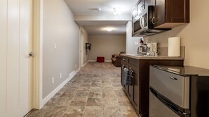 A kitchen with dark wooden cabinets, a stainless steel refrigerator, and a tiled floor. - Cove On A Hill - Entire (2Bdrm & Full Bath) Basement Suite (Calgary)
