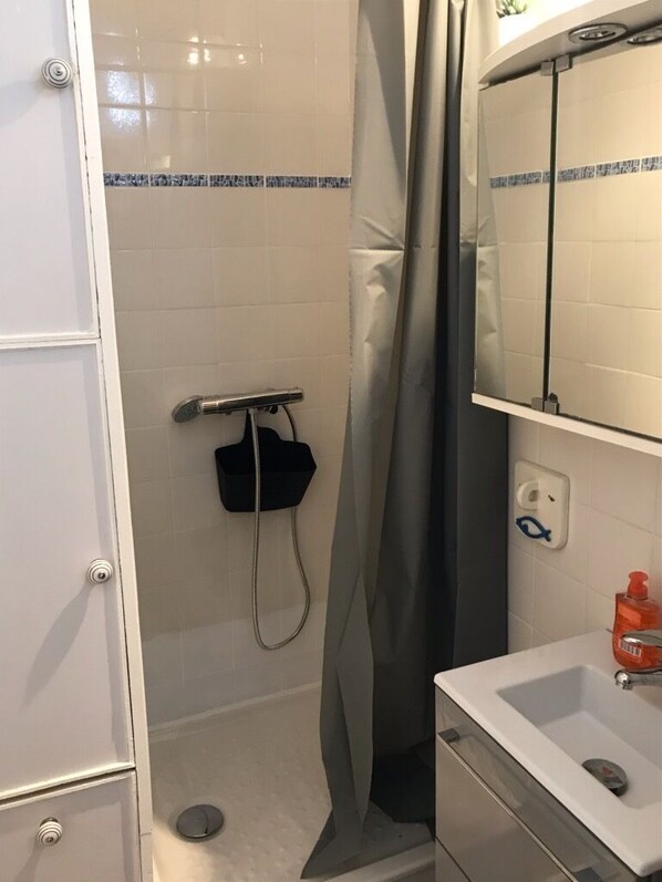 A bathroom with a shower, a sink, and a mirror. - Cozy studio, close to the beach, with a real bed and parking (Arcachon)
