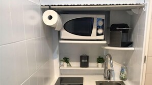 A compact kitchen with a microwave, sink, and a small cabinet.