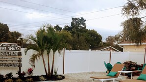 A swimming pool with lounge chairs and a signboard. - Tropical Tiny House (New Port Richey)