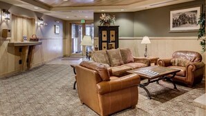 A spacious lobby with a leather sofa, a wooden reception desk, and a framed historical photo on the wall. - Silver Mill 8153 by Summit County Mountain Retreats (Keystone)