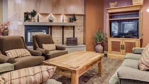 A cozy living room with a fireplace, wooden furniture, and a television. - Silver Mill 8153 by Summit County Mountain Retreats (Keystone)